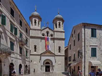 Imposing church with two towers in the historic old town, flanked by sand-coloured buildings under