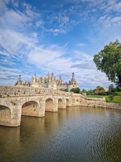 A picturesque stone bridge spans the still water leading to the magnificent Chateau de Chambord.