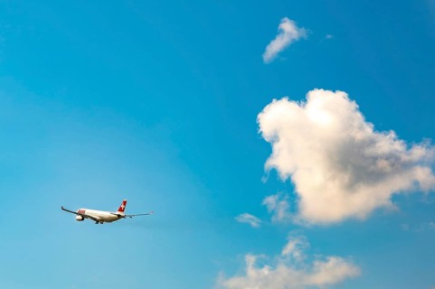 Swiss Airlines Passenger Airplane Flying Against Blue Sky and Clouds in a Sunny Summer Day From the