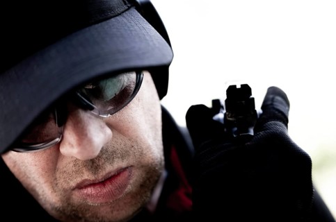 Face of a Man with Cap and Protection Eyeglasses Holding a Handgun Backward in Switzerland