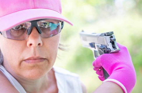 Portrait of a Woman with Cap and Protection Eyeglasses Holding a Handgun Backward in Switzerland