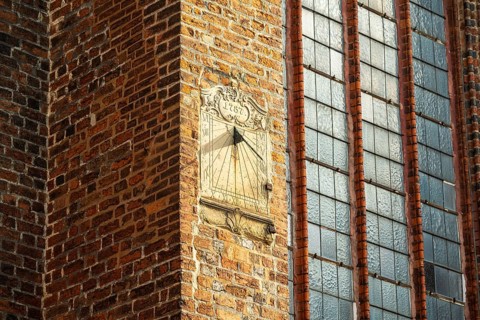 Sundial on a red brick wall next to large Gothic windows, cathedral, Verden an der Aller, Lower