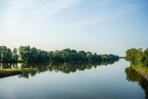 A calm river with green trees and blue sky, peaceful landscape, Weser cycle path, Nienburg Weser