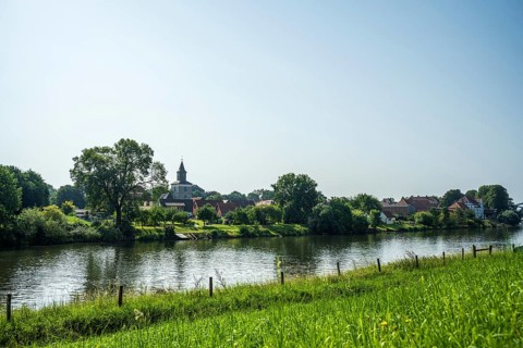 Rural view of a village with a church by the river, surrounded by green nature and a peaceful
