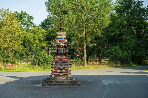 Colourful brick sculpture in a park with green trees in the background in the afternoon, Bücken,