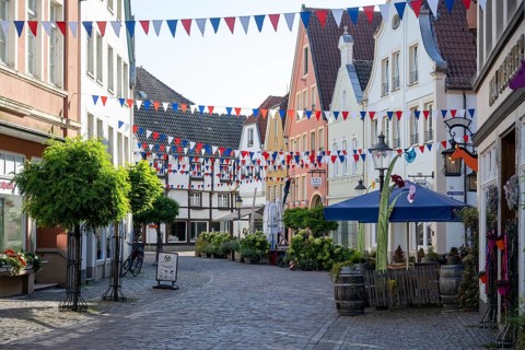 Colourfully decorated street in an old town with garlands and plants along the pavements,