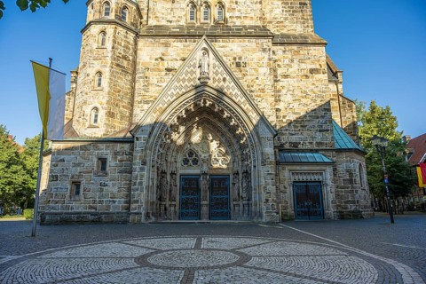Entrance to a church with richly decorated arch, brick façade and paved forecourt, St Laurentius
