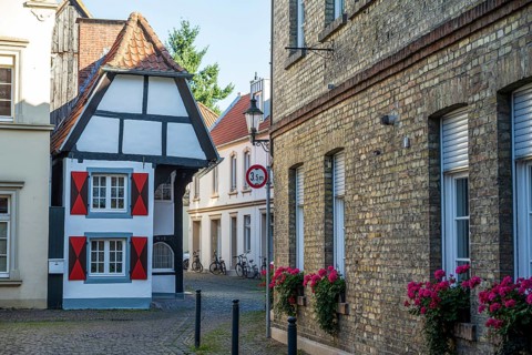 Small half-timbered house in narrow street decorated with flowers, historic surroundings,