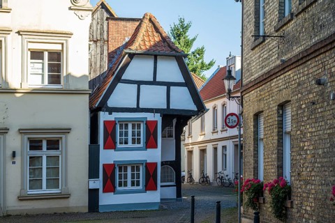 Small half-timbered house in a narrow lane, decorated with eye-catching red shutters, Warendorf,