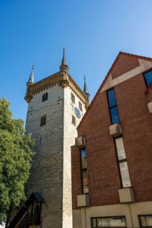 Historic tower and modern building, surrounded by trees, under a blue sky, tower of the old St