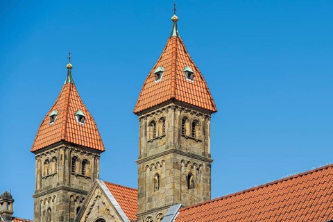 Two Gothic church towers with red tiled roofs under a clear blue sky, St Mary's Church in
