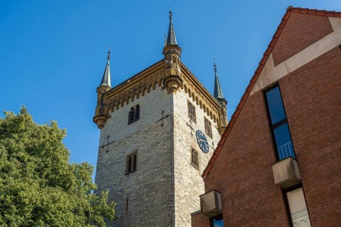 Old tower next to a modern building, in a clear blue sky, tower of the old St Mary's Church,
