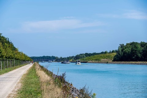 Canal with boats and clear sky. Calm water surrounded by nature and a gravel path, Dortmund-Ems