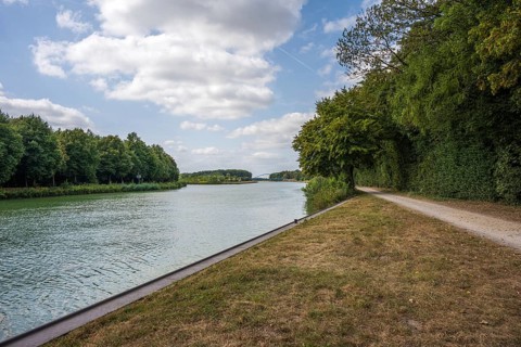 Idyllic river with adjoining path, framed by trees under a partly cloudy sky, Senden, Münsterland,