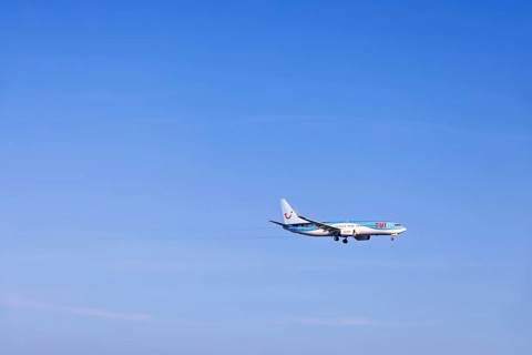Passenger plane with tourists from the travel company Tui flying on a clear blue sky, Mallorca,