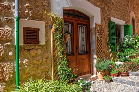 Entrance to residential house in an idyllic old cobblestone alley with green plants and flowers at