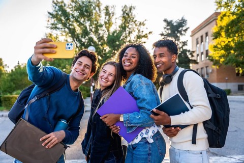 Group of smiling multi ethnic students standing outdoors on campus, celebrating friendship, youth,
