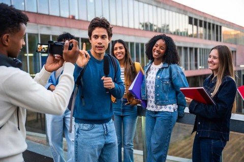 Group of diverse university students filming an interview on campus, one student speaking into a