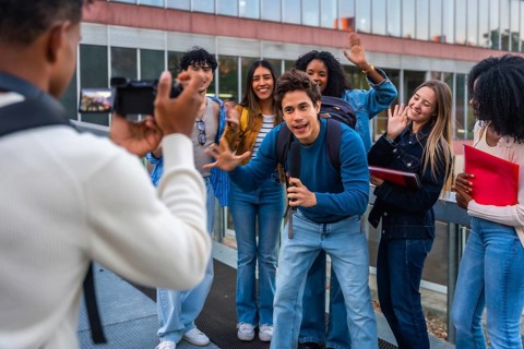 University student filming diverse group of friends on campus, capturing authentic smiles and