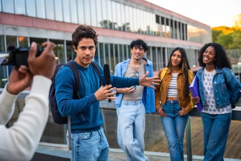 Young diverse students collaborating on a media project, a man holding a boom microphone