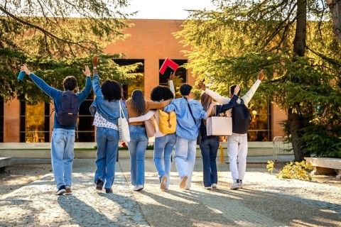 Group of diverse university students walking together on campus, embracing friendship and
