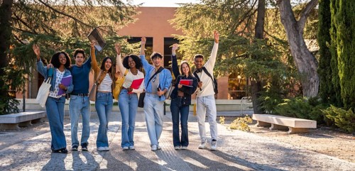 Group of young, happy, diverse university students standing together, raising their hands in