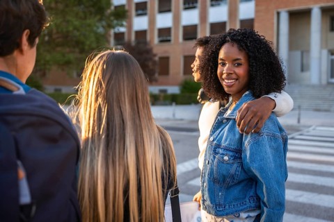 Diverse group of young students smiling and walking on a university campus during sunset,
