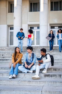 Diverse group of young adult students interacting and studying on the stone steps of a university