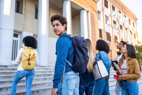 Group of young adult students walking on a university campus building staircase, representing