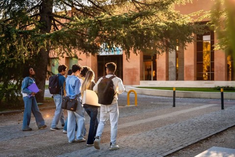 Group of diverse university students with backpacks and folders walking together on campus, heading
