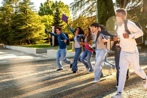 Group of excited multiracial students. Wearing casual clothes and carrying backpacks and books.