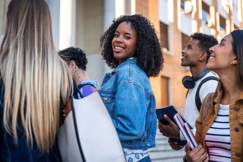 Group of multi ethnic university students walking together on campus, smiling, and looking around,