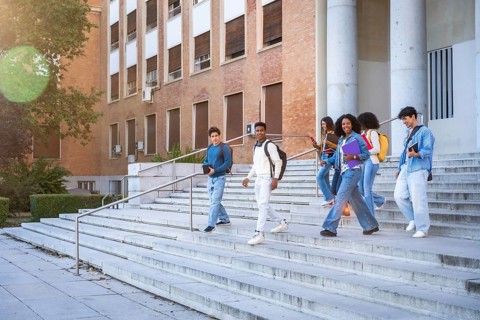 Diverse group of young students smiling, talking, and walking down the outdoors stairs of a