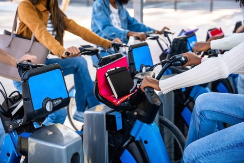 Diverse university students sharing blue urban bikes, enjoying eco friendly campus commutes and