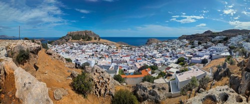 Panorama of the town of Lindos with Acropolis with white buildings by the sea under a blue sky,