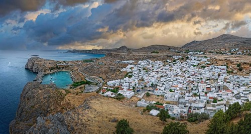 Atmospheric view of the coastal town of Lindos under a dramatic sky at dusk, Acropolis, Lindos,