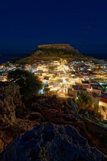 Night picture of the brightly lit town of Lindos and the ancient Acropolis on a rock in the