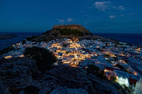 Picturesque Lindos with the ancient Acropolis at dusk with glowing houses and castle in the