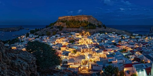 Illuminated town of Lindos with the ancient acropolis and sea in the background, surrounded by