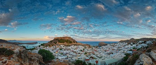 Picturesque Lindos with the ancient Acropolis in the evening light, surrounded by rocks and sea