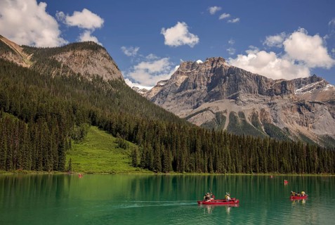 Canoes on the stunning Emerald Lake with the Canadian Rocky Mountains terrain and lush forests