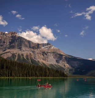 Canoeists on Emerald Lake with the Canadian Rocky Mountains and clouds reflected in the calm water