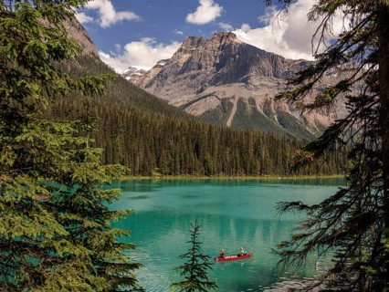 Canoe with explorers on Emerald Lake surrounded by the Canadian Rocky Mountains within Yoho