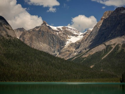 Snowy mountains of the Canadian Rocky Mountains and Emerald Lake with green forest expanse inside