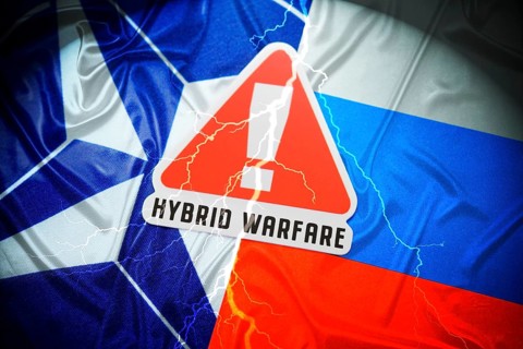 The flags of NATO and Russia with danger sign and inscription Hybrid Warfare, symbolic photo of