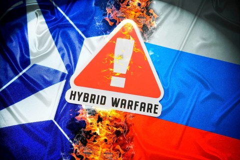 The flags of NATO and Russia with danger sign and inscription Hybrid Warfare, symbolic photo of