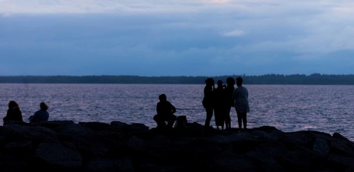 Group of silhouetted figures by a municipal lake at dusk in Ottawa, Ontario, Canada, North America