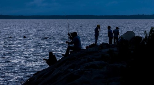 Group of people fishing at night, silhouetted against the water in Ottawa, Ontario, Canada, North
