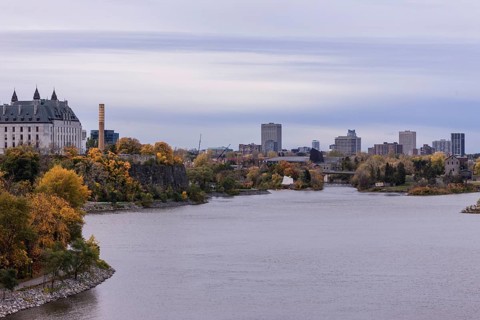 A city skyline seen across a the Ottawa River during an overcast autumn day in Ottawa, Ontario,