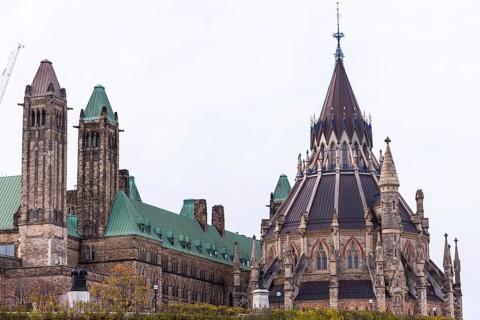 The Canadian Parliament Building with gothic architecture and towers against a cloudy sky in